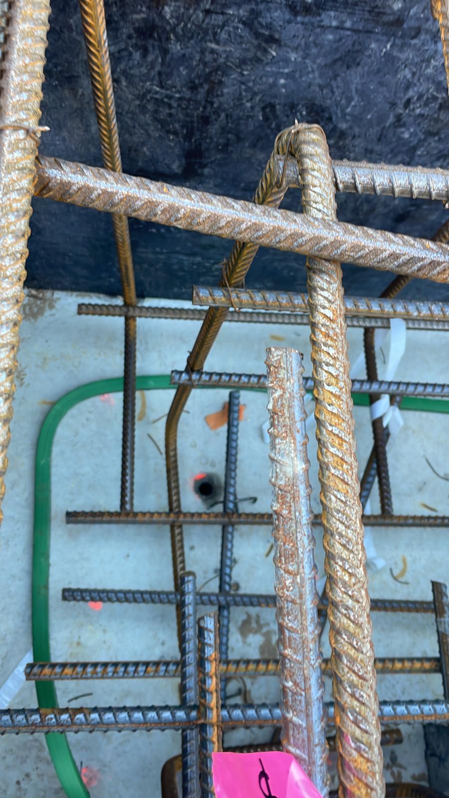 Steel rebar cage installed over a tanked base with green waterstop against a black tanked wall