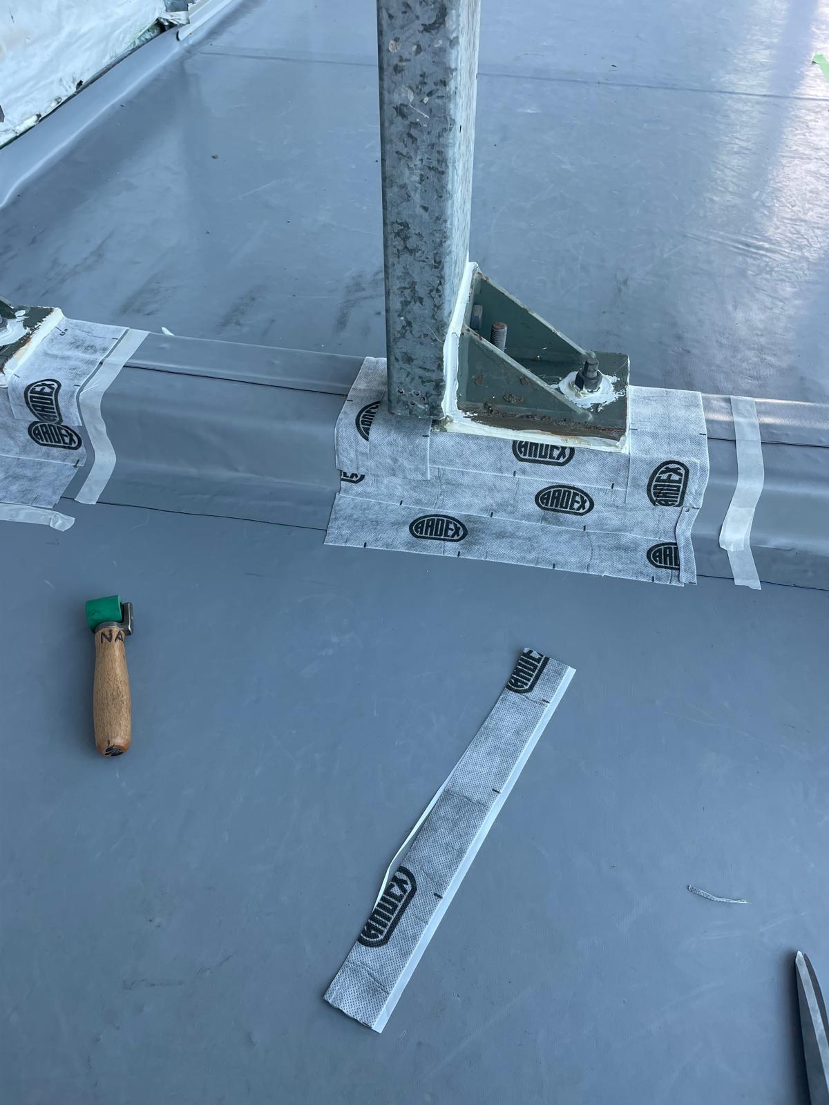 Reinforcing tape detailing around a steel post base on a roof membrane