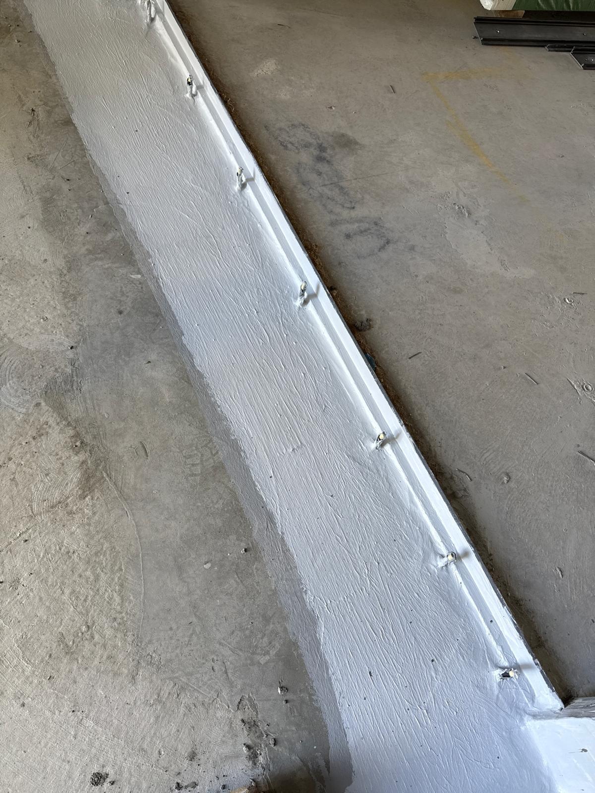 Set down upstand coated in white membrane along a concrete slab