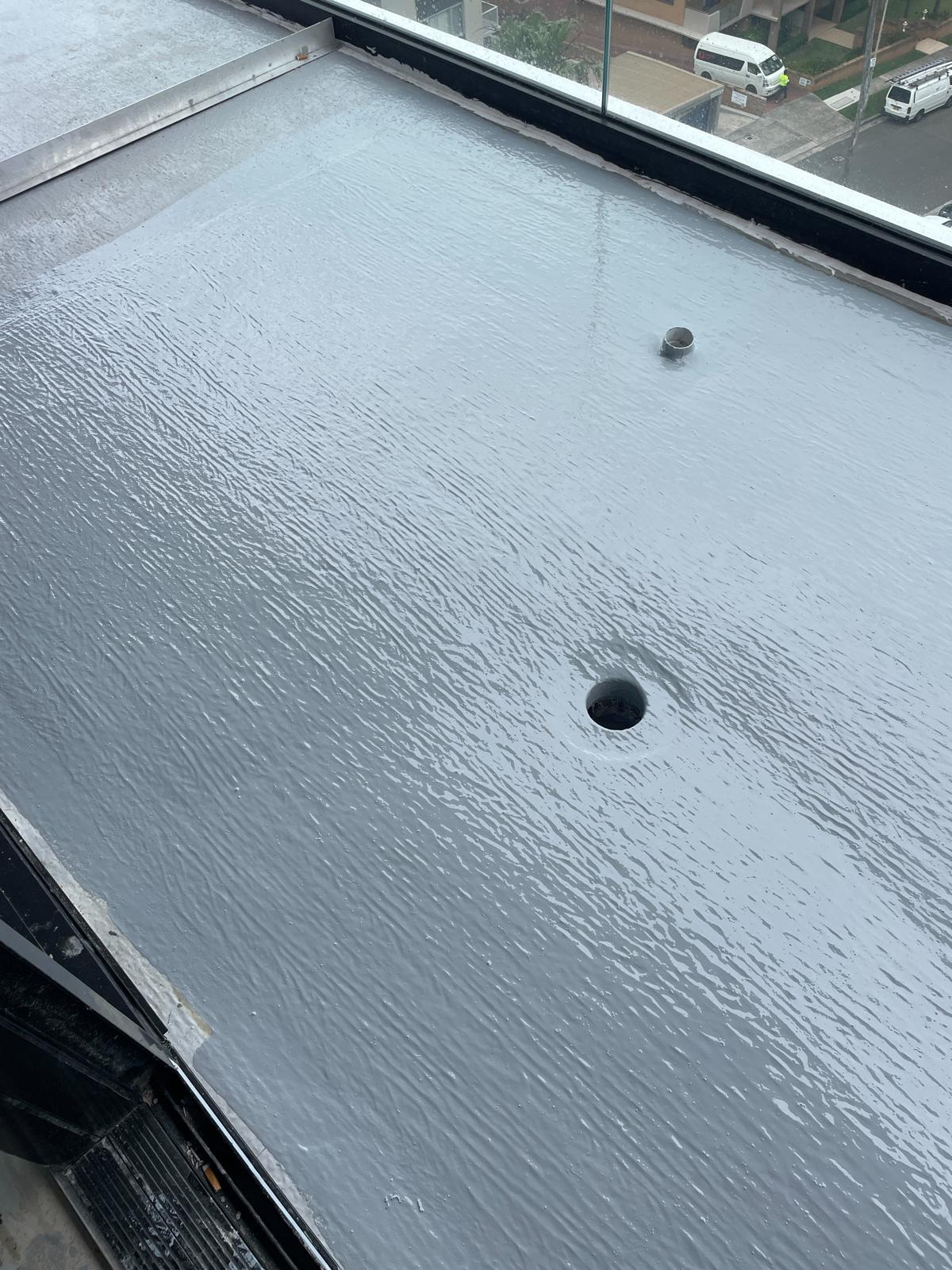 Balcony deck coated in grey membrane with sealed drainage outlets