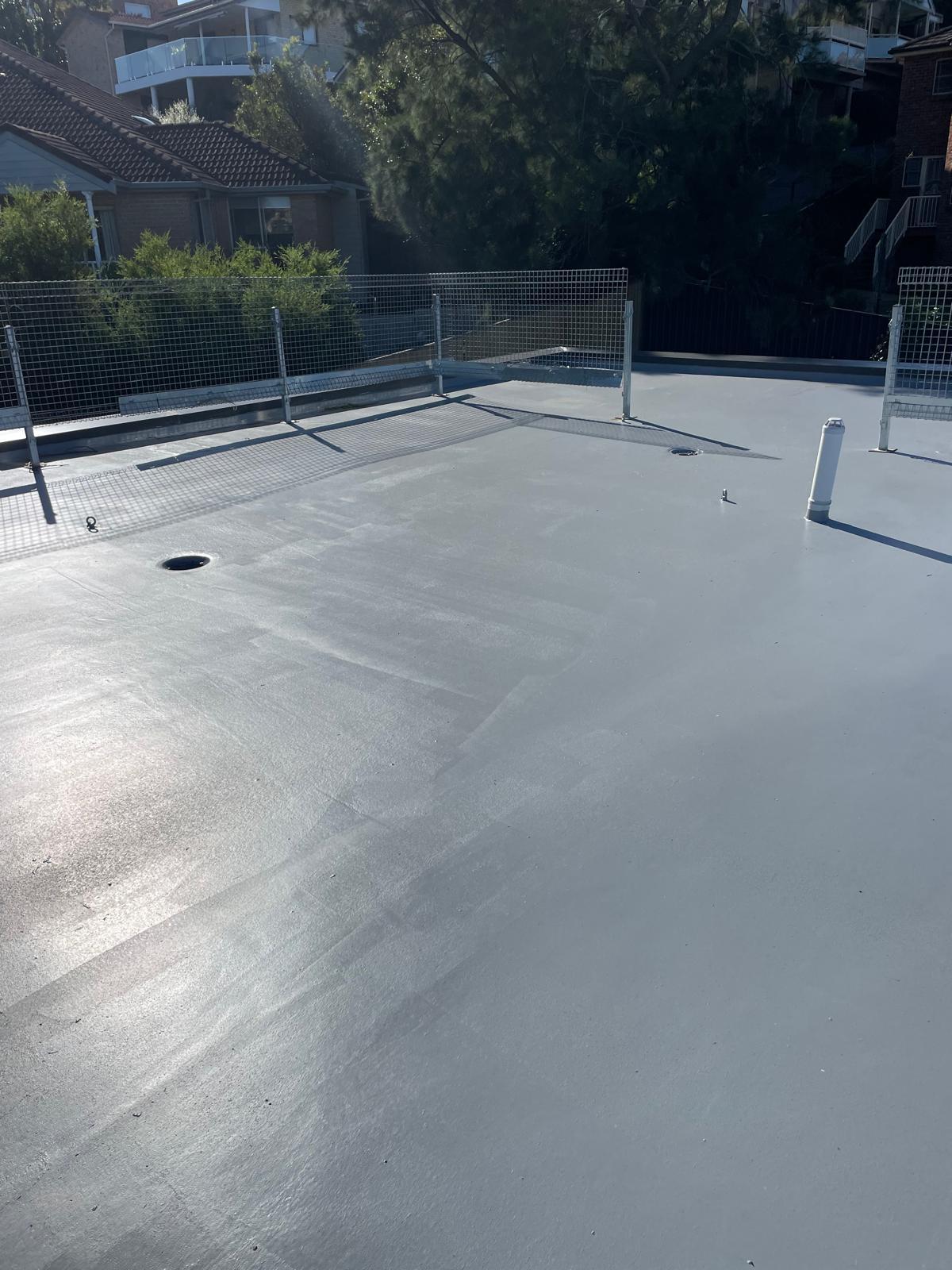 Flat roof finished in grey waterproofing membrane with sealed drainage outlets
