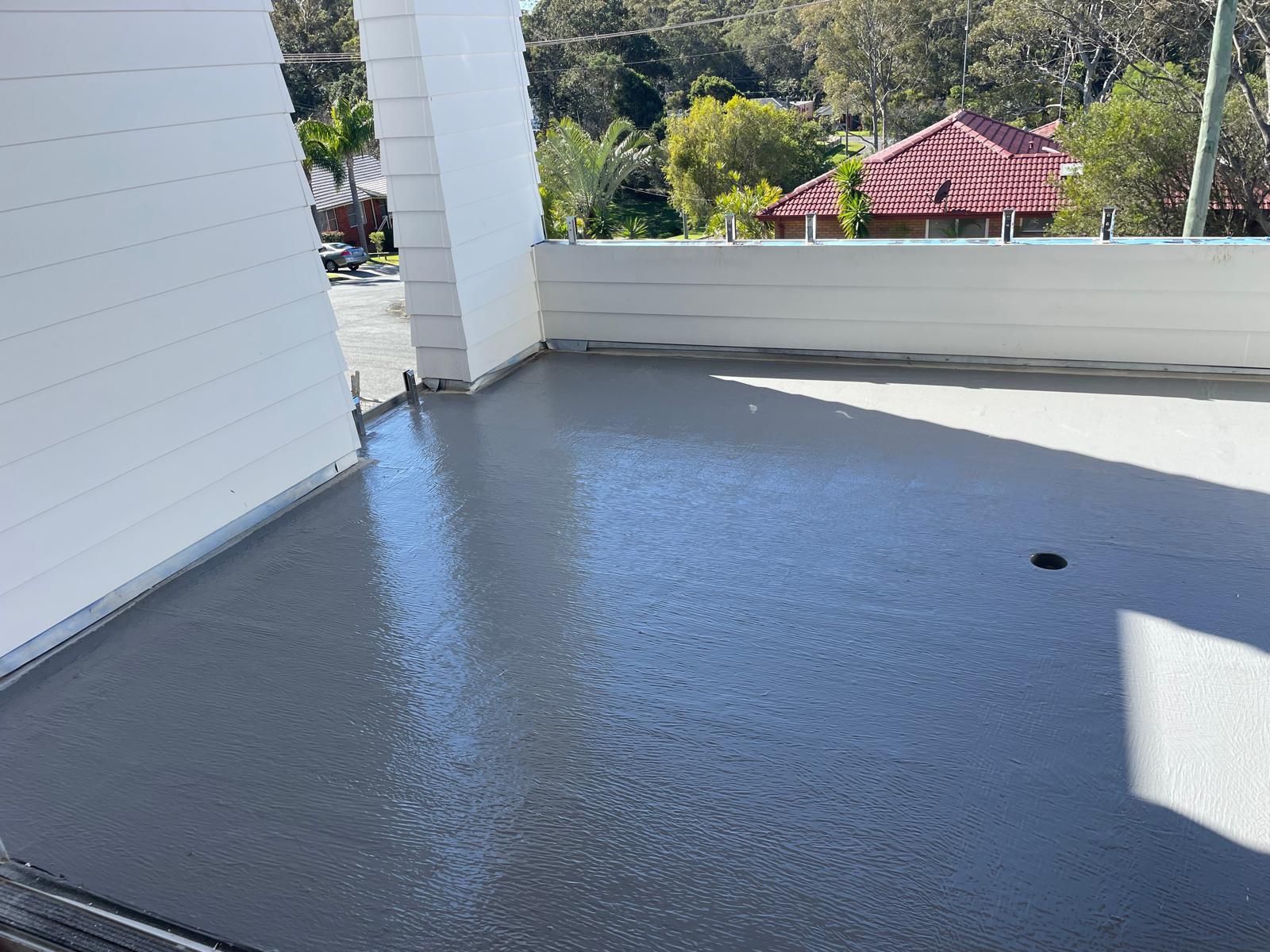 Wide balcony deck coated in grey waterproofing membrane with sealed perimeter
