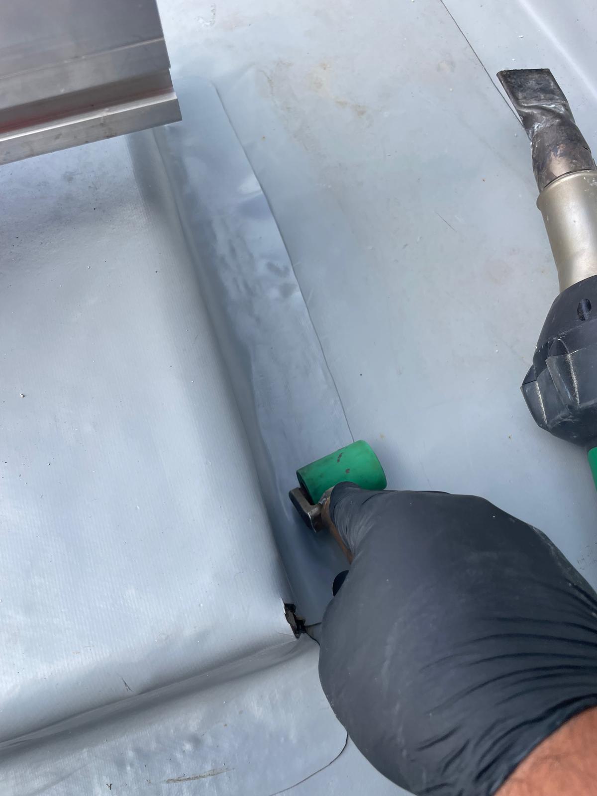 Hot air welding a seam in a roof sheet membrane with a hand roller