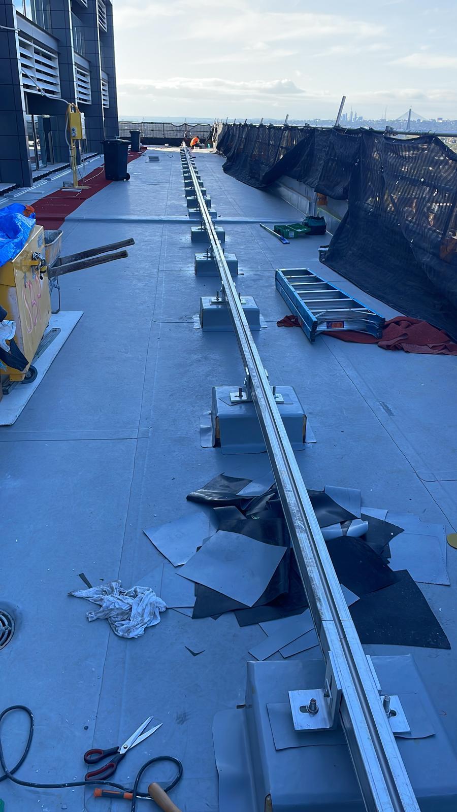 Rooftop sheet membrane installed beneath a screen wall track on a high-rise