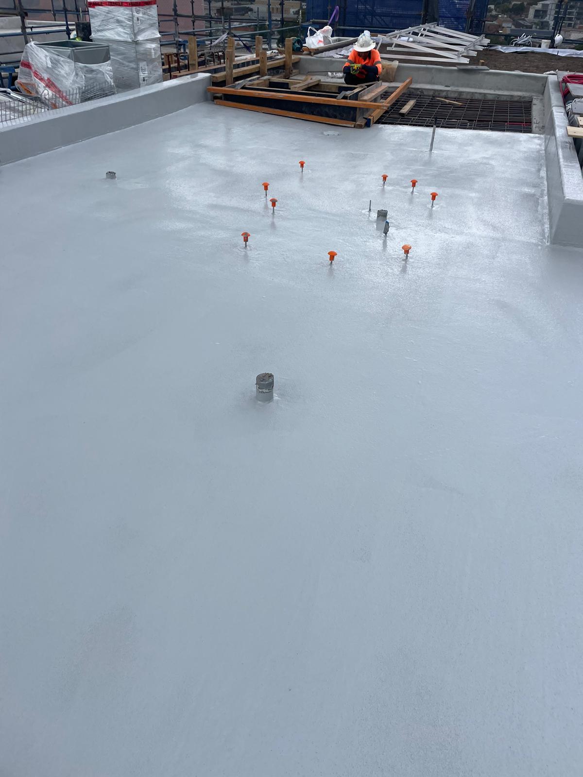 Roof slab on a construction site coated in waterproofing membrane around penetrations