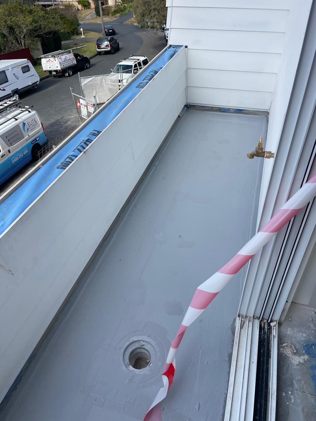 Balcony floor waterproofed in grey membrane around the floor waste outlet